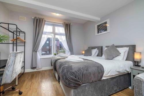 a bedroom with two beds and a window at Ealing Manor - 6 beds 3 sofa beds sleeps 9 ppl in Greenford