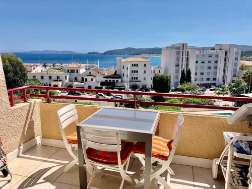 une table et des chaises sur un balcon avec vue sur une ville dans l'établissement Studio Piscine vue mer Le Lavandou, au Lavandou