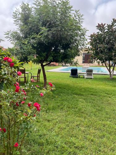 a park with benches and a tree and flowers at Villa Zaouiat in Ben Guemoud