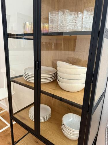 a glass cabinet filled with white plates and dishes at NINOA holidays in Petrcane