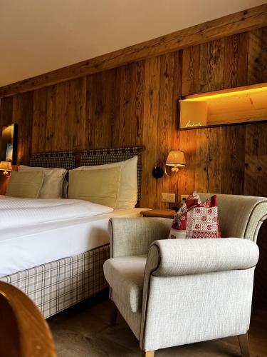 a bedroom with a bed and a couch and a chair at Hotel Berghof in Zermatt