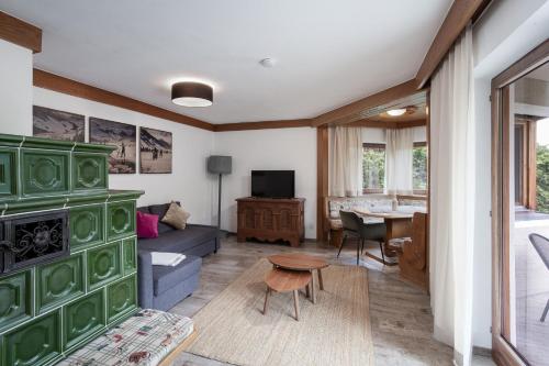 a living room with a green fireplace and a table at Alpine View Apartments in Niedernsill