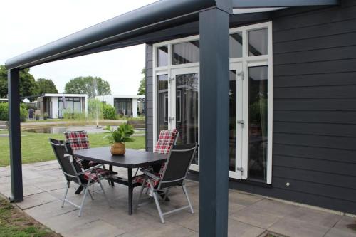 a patio with a table and chairs at Vakantiehuis met vijverzicht in Lathum