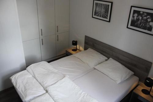 a bed with white sheets and pillows in a bedroom at Vakantiehuis met vijverzicht in Lathum