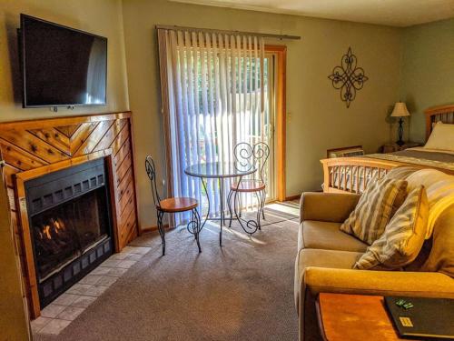 a bedroom with a living room with a fireplace and a bed at Springbrook Inn AuSable in Houghton Lake