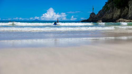a person riding a wave on a surfboard in the ocean at Beach Front Litore in Shimoda