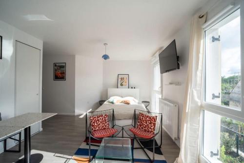 a bedroom with a bed and a table and two chairs at Suite POP 92 proche gare, stade de France, Parking in Osny