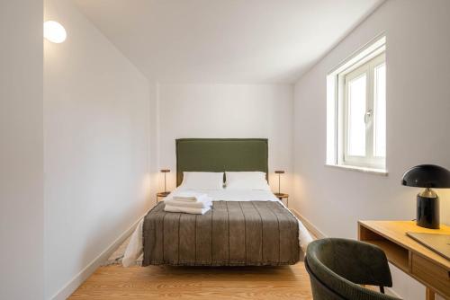 a bedroom with a bed and a desk and a window at Azul Downtown Apartments in Coimbra