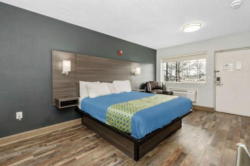 a hotel room with a bed and a chair at Grove City Travel Inn South Columbus in Grove City