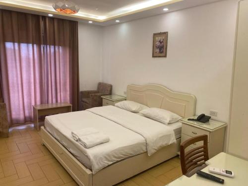 a bedroom with a bed and a desk with a phone at فندق اربد بلازا in Irbid
