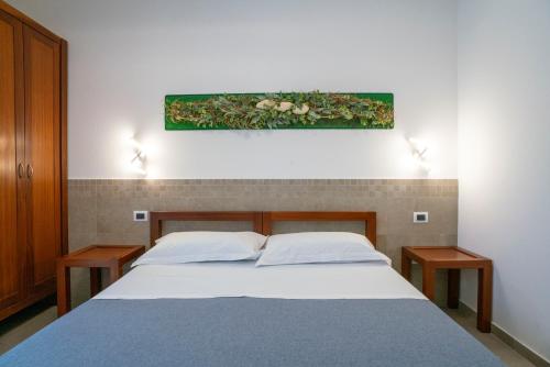 a bedroom with a bed with two tables and a painting on the wall at Petit Hotel in Milazzo
