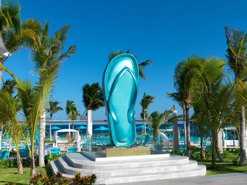 a blue sculpture in front of a resort with palm trees at Margaritaville Island Reserve Riviera Maya - An Adults Only Karisma All-Inclusive Experience in Puerto Morelos