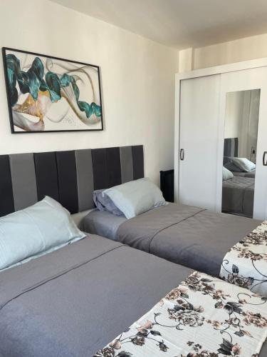 a bedroom with two beds and a painting on the wall at Apartamento ao Lado do Centro de Convenções do Rio Centro! 8 min da praia do Recreio dos Bandeirantes in Rio de Janeiro