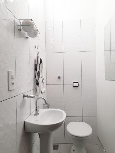 a white bathroom with a sink and a toilet at Casa Loft da Orla in Barra Bonita