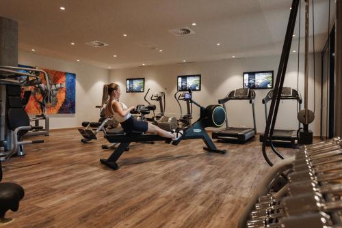 a woman exercising in a gym with machines at Sportresidenz Zillertal - 4 Sterne Superior in Uderns