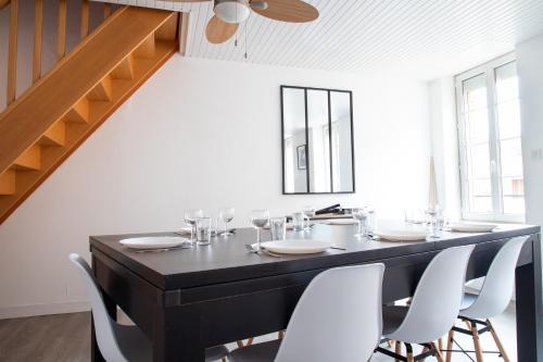une salle à manger avec une table noire et des chaises blanches dans l'établissement Grand Duplex avec billard, à Villeneuve-Tolosane