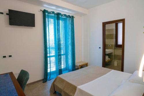 a bedroom with a bed and a window with blue curtains at Petit Hotel in Milazzo
