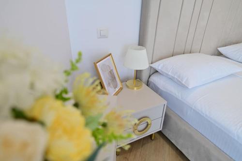 a bedroom with a bed and a nightstand with a clock and flowers at FLH - SIBIU - The Evolution LUXURY Apt - 2 Bedrooms, 1 Livingroom, 2BA with 3 ACs Units and Panoramic view - Sleeps 6 - Shopping City Mall in Şelimbăr