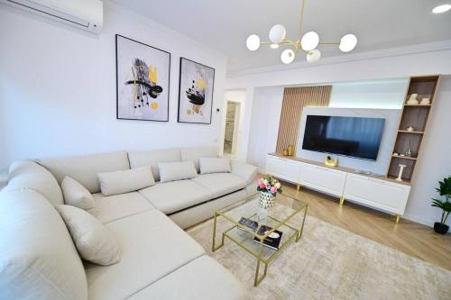 a white living room with a white couch and a tv at FLH - SIBIU - The Evolution LUXURY Apt - 2 Bedrooms, 1 Livingroom, 2BA with 3 ACs Units and Panoramic view - Sleeps 6 - Shopping City Mall in Şelimbăr