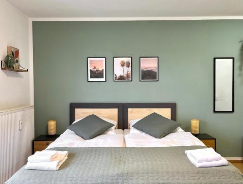 a bedroom with two beds and three pictures on the wall at Salí - Essen - Studioapartments in Essen