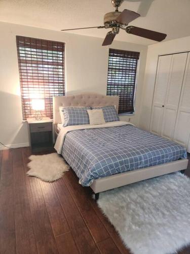 a bedroom with a bed with a blue blanket and two windows at Beautiful specious pool house, feel home in Port Richey