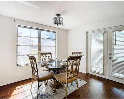 a dining room with a table and chairs and windows at Beautiful specious pool house, feel home in Port Richey