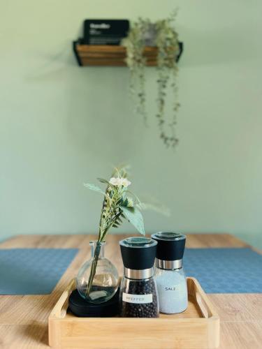a wooden tray with three bottles and a vase with flowers at Salí - Remscheid - Apartmenthaus in Remscheid