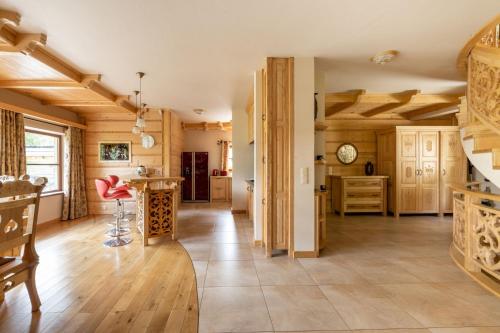 een grote keuken met houten vloeren en een rode stoel bij Rezydencja Sywarne Lux Spa in Kościelisko