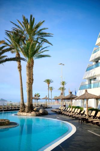 a pool at the beach with palm trees and chairs at Alua Golf Trinidad in Roquetas de Mar