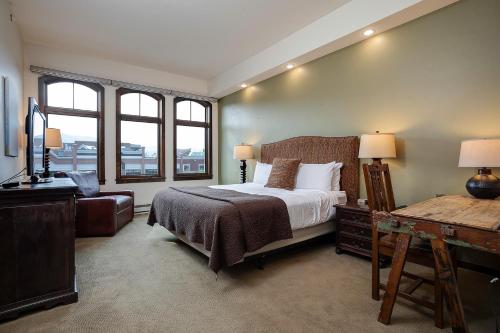 Un dormitorio con una cama y un escritorio y dos ventanas. en Expansive Luxury Condo - Downtown - Summer AC, en Steamboat Springs