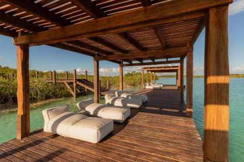 a wooden dock with lounge chairs on the water at Boca de Agua Bacalar in Bacalar