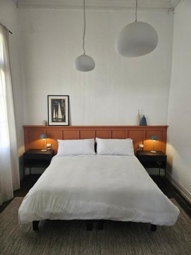 a bedroom with a large white bed with two tables at La Puerta Roja in Valparaíso