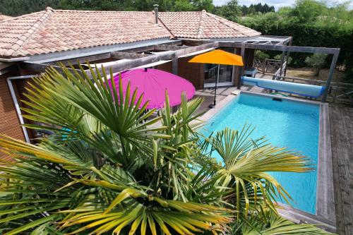 - une piscine avec un parasol rose et un parasol violet dans l'établissement Villa Ti'plage, piscine privative, proche océan, à Saint-Paul-en-Born