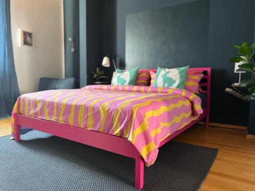 Un dormitorio con una cama rosa con una manta colorida. en Hencoop 2 room apartment kitchen bathroom and optional Sauna, en Kaiserslautern