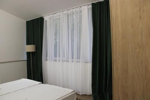 a bedroom with a bed and a window with green curtains at JR's House in Yerevan
