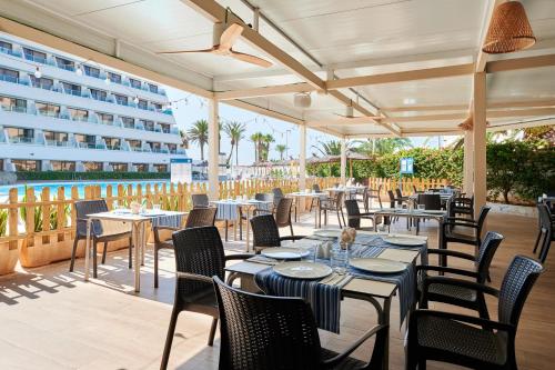 a restaurant with tables and chairs and a building at Alua Golf Trinidad in Roquetas de Mar