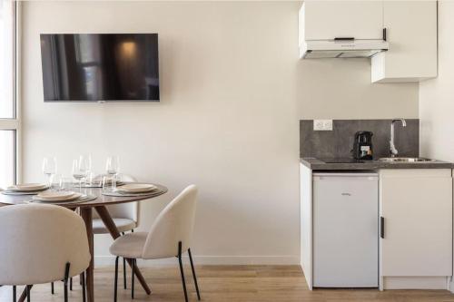 - une cuisine avec une table, des chaises et des verres à vin dans l'établissement Cosy Studio pour 3 aux Portes de Paris, à Le Pré-Saint-Gervais
