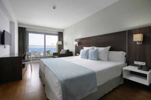 a hotel room with a large bed and a desk at Alua Golf Trinidad in Roquetas de Mar