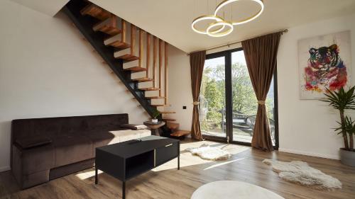 a living room with a couch and a staircase at Blissful Resort - Valea Doftanei in Teşila