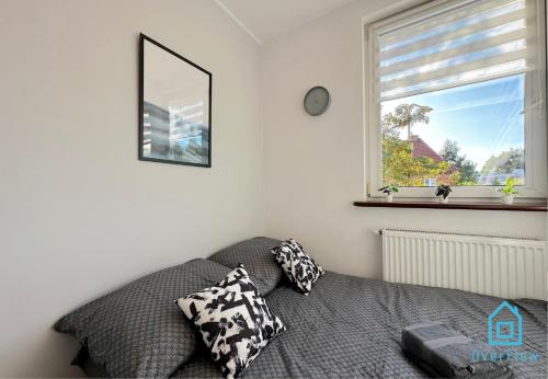 a bedroom with a bed with pillows and a window at Batory Room - Peaceful Retreat, 10 Minutes to Gdańsk Old Town & Seaside in Zaspa