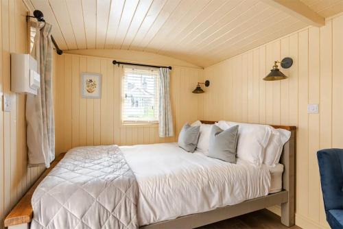 a bedroom with a bed with white sheets and a window at Shepherd's Hut, Bath in Bath