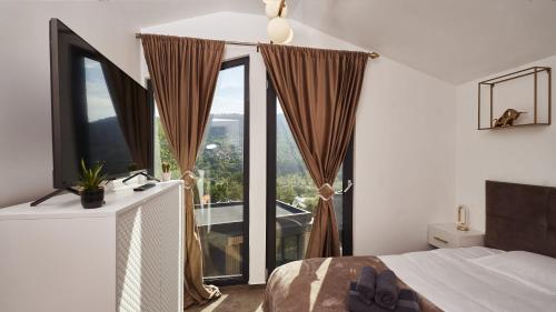 a bedroom with a bed and a large window at Blissful Resort - Valea Doftanei in Teşila