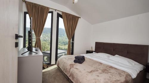 a bedroom with a bed with a large window at Blissful Resort - Valea Doftanei in Teşila