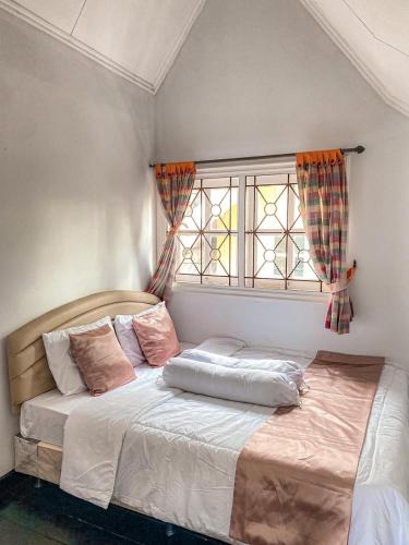 une chambre avec un grand lit avec une fenêtre dans l'établissement Villa Kota Bunga Aeshtetic By akuvilla, à Cikundul