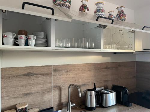 a kitchen with white cabinets with dishes and a sink at Penzion U Blechy a Švába in Mikulčice