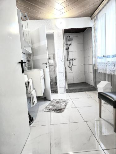 a bathroom with a shower and a white tile floor at Alpenresorts Landeck in Landeck
