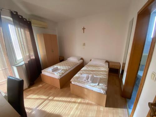 two beds in a small room with a cross on the wall at Guest House Regina Mundi in Međugorje