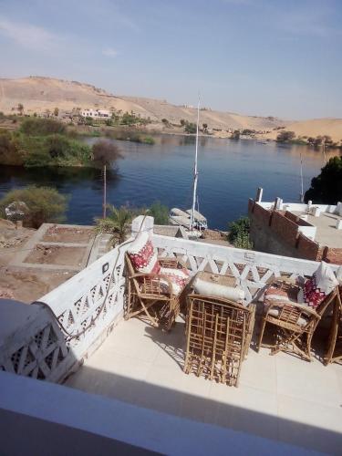 a view of a river with chairs and a bridge at Nubian Life Nile View in Aswan