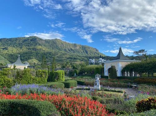 a garden with flowers and a building and mountains in the background at เดอะบลูสกายเขาค้อโซนปราสาทJeab in Ban Lam Ri
