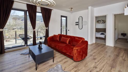 a living room with a red couch and a table at Blissful Resort - Valea Doftanei in Teşila